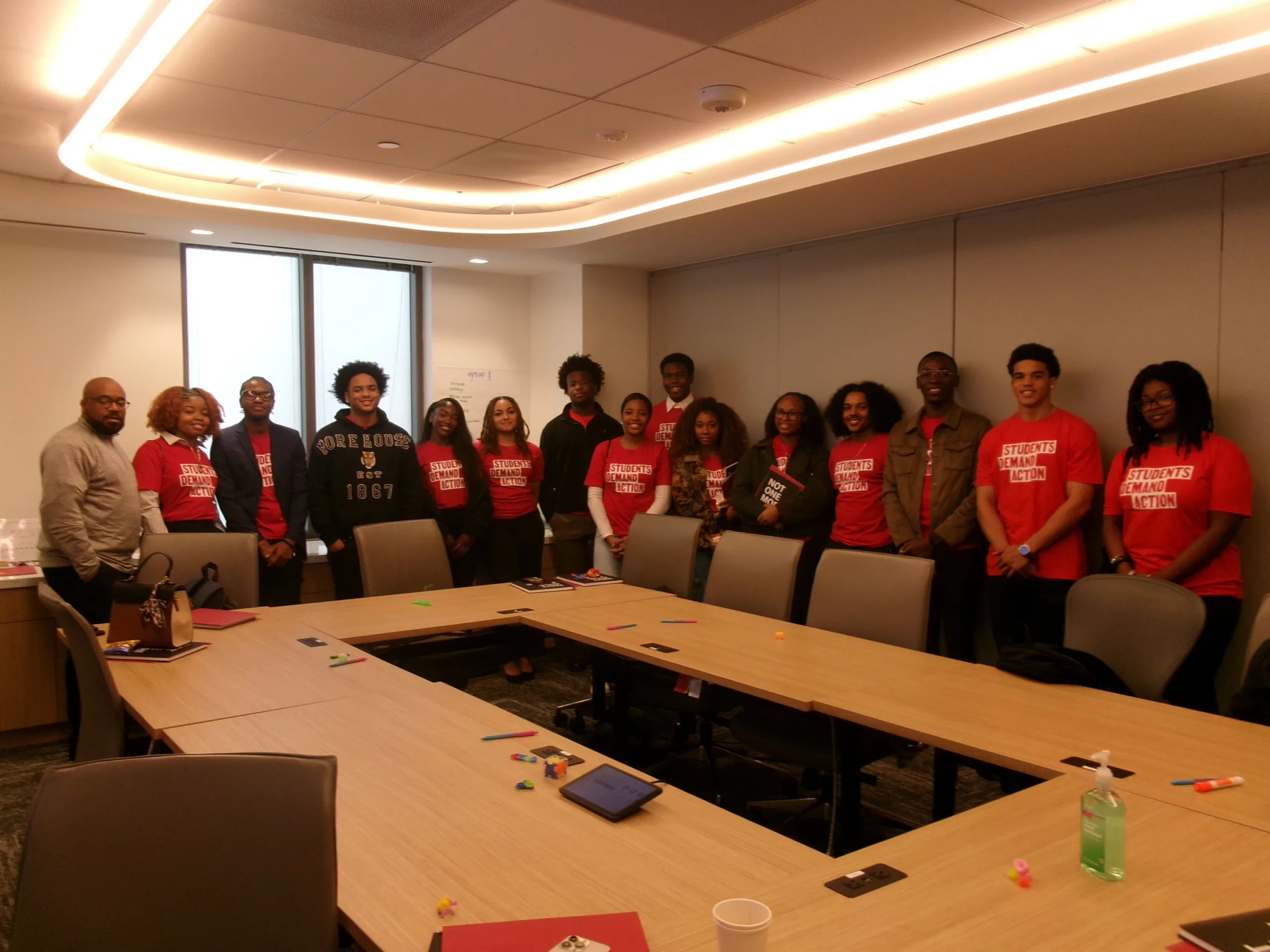15 students pose for a photo with a presenter at the Young Changemakers Summit. All the students are wearing red Students Demand Action t-shirts.