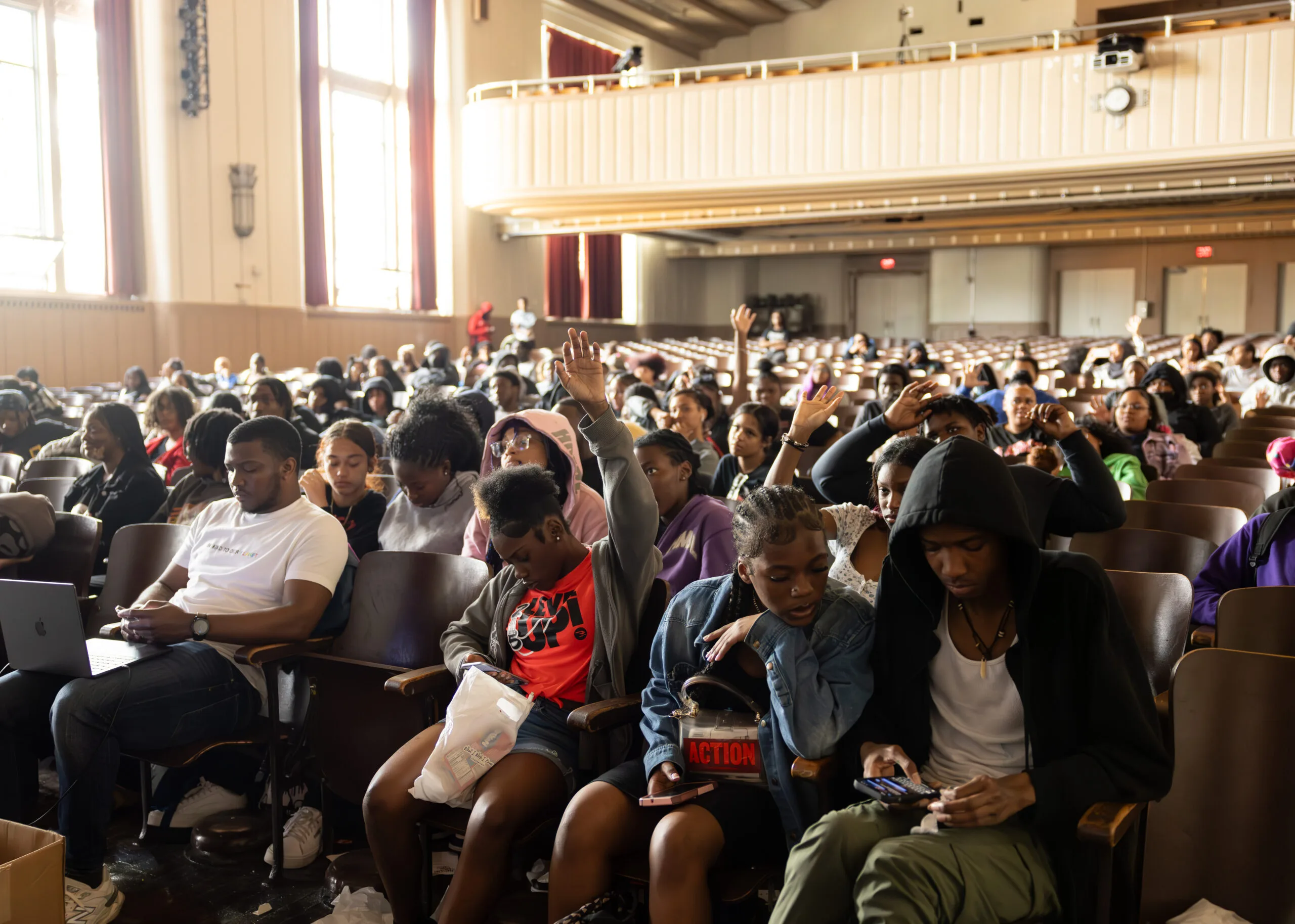 Conflict resolution tour attendees respond to something a speaker has just said; many raise their hands in the air.