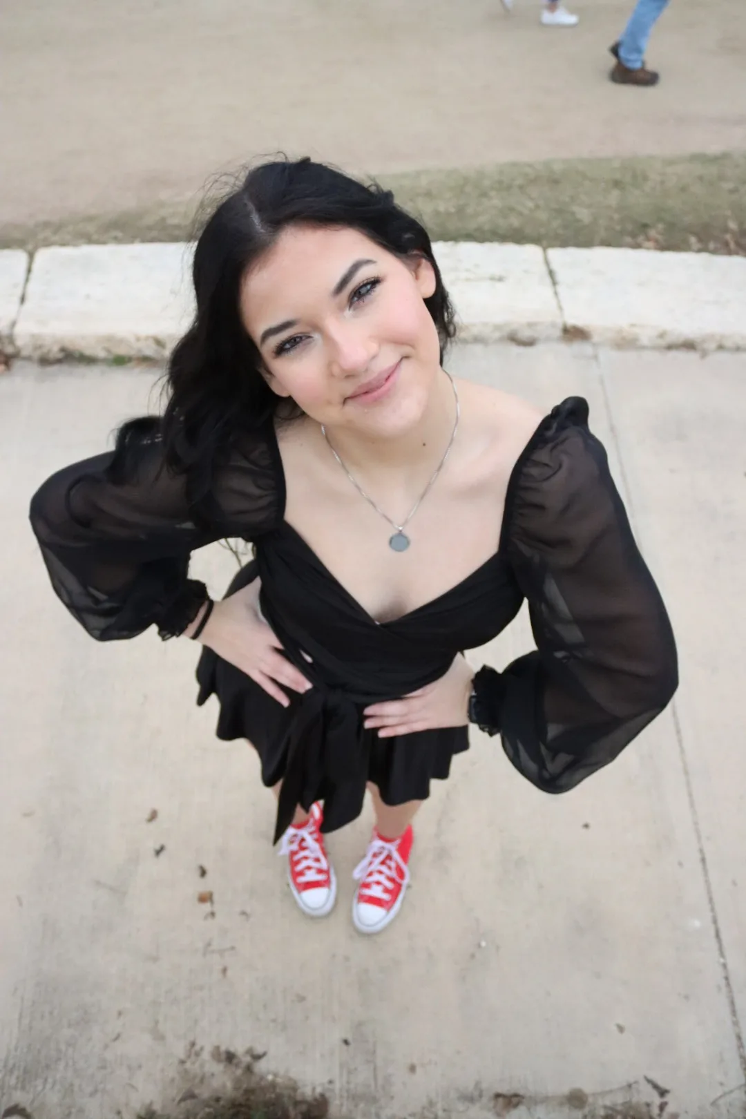 Hayden Presley, a Students Demand Action Text Team Captain, poses for a photo taken from a high angle. Hayden is wearing a black dress with bright red high-top sneakers.