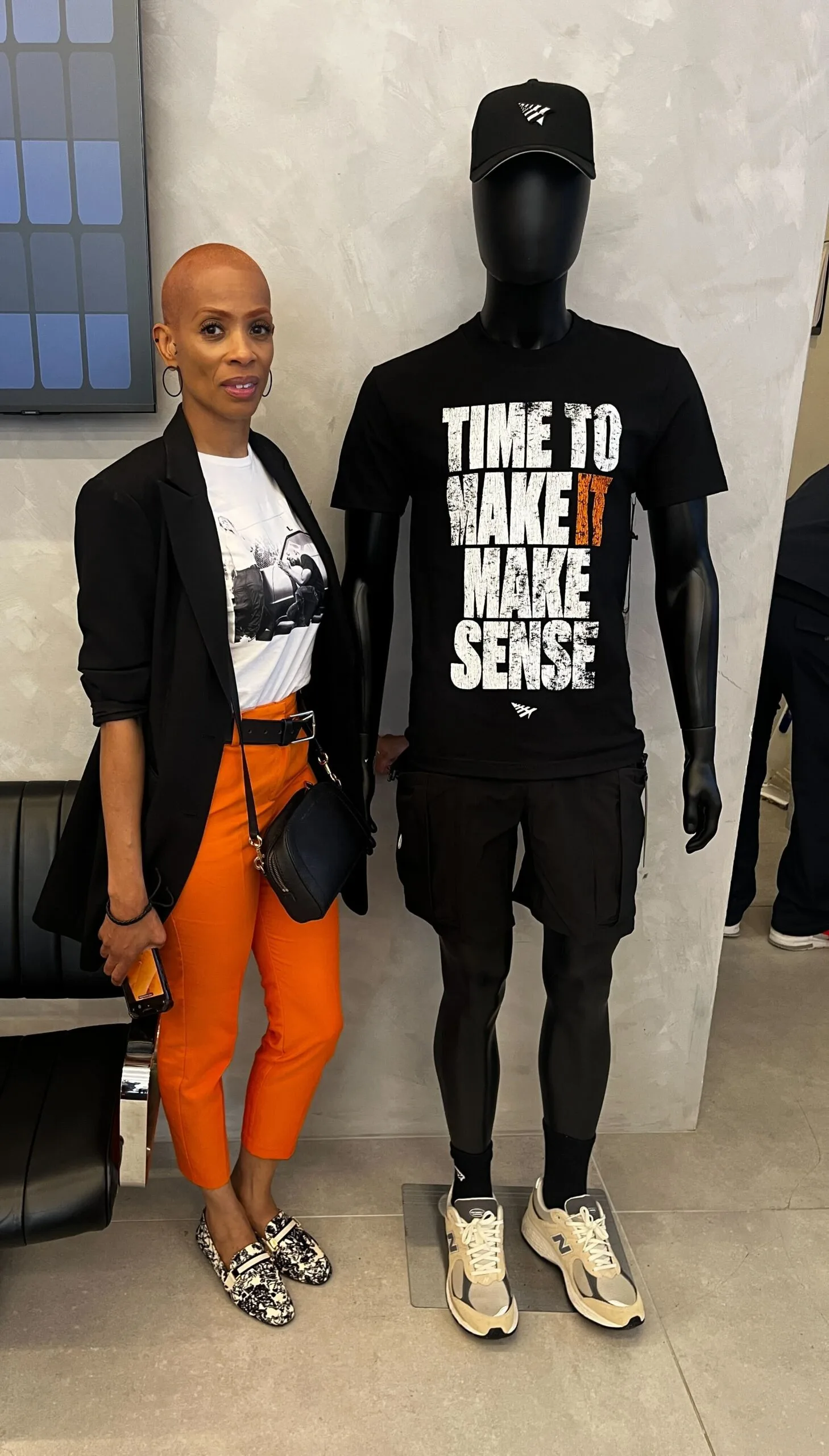 Neal McDonald's mother stands to the right of a mannequin that is modeling a black Paper Planes baseball cap and the black "Time to Make It Make Sense" memorial t-shirt.
