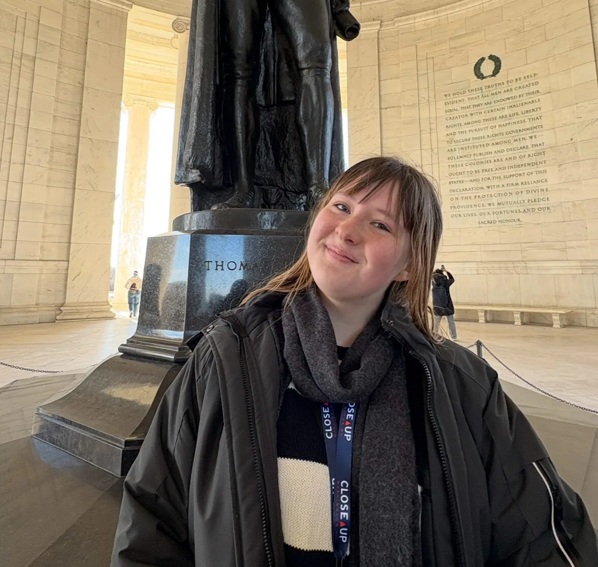 Kaya Kutzly, a Students Demand Action Text Team Captain, poses for a photo in front of the Thomas Jefferson memorial in D.C. Kaya wears a jacket and scarf.