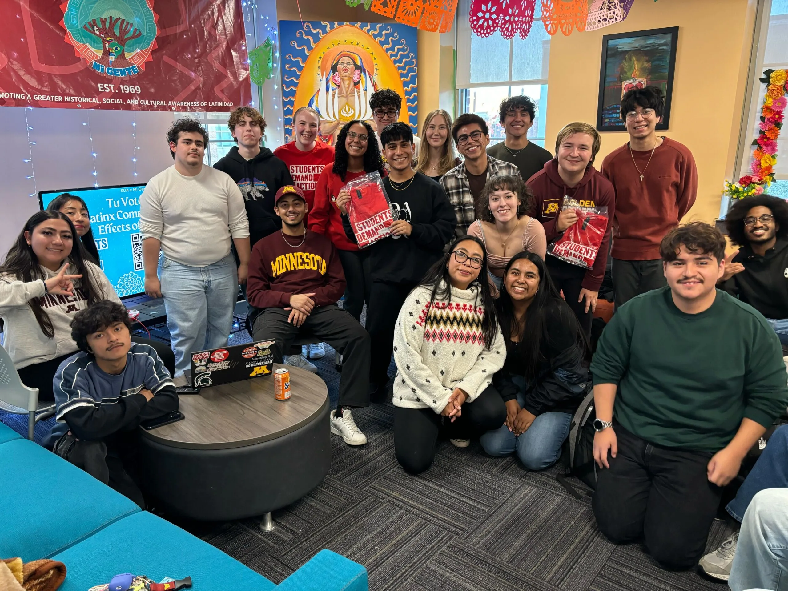 A group of around 20 Students Demand Action and Mi Gente group members at the University of Minnesota pose for a group photo.