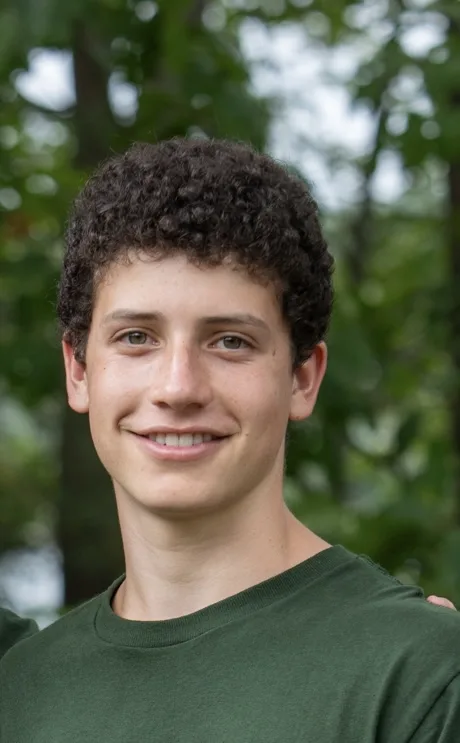 Aidan Lapatine, a Students Demand Action Text Team Captain, poses for a professional photo outside while wearing a green crew-neck shirt.