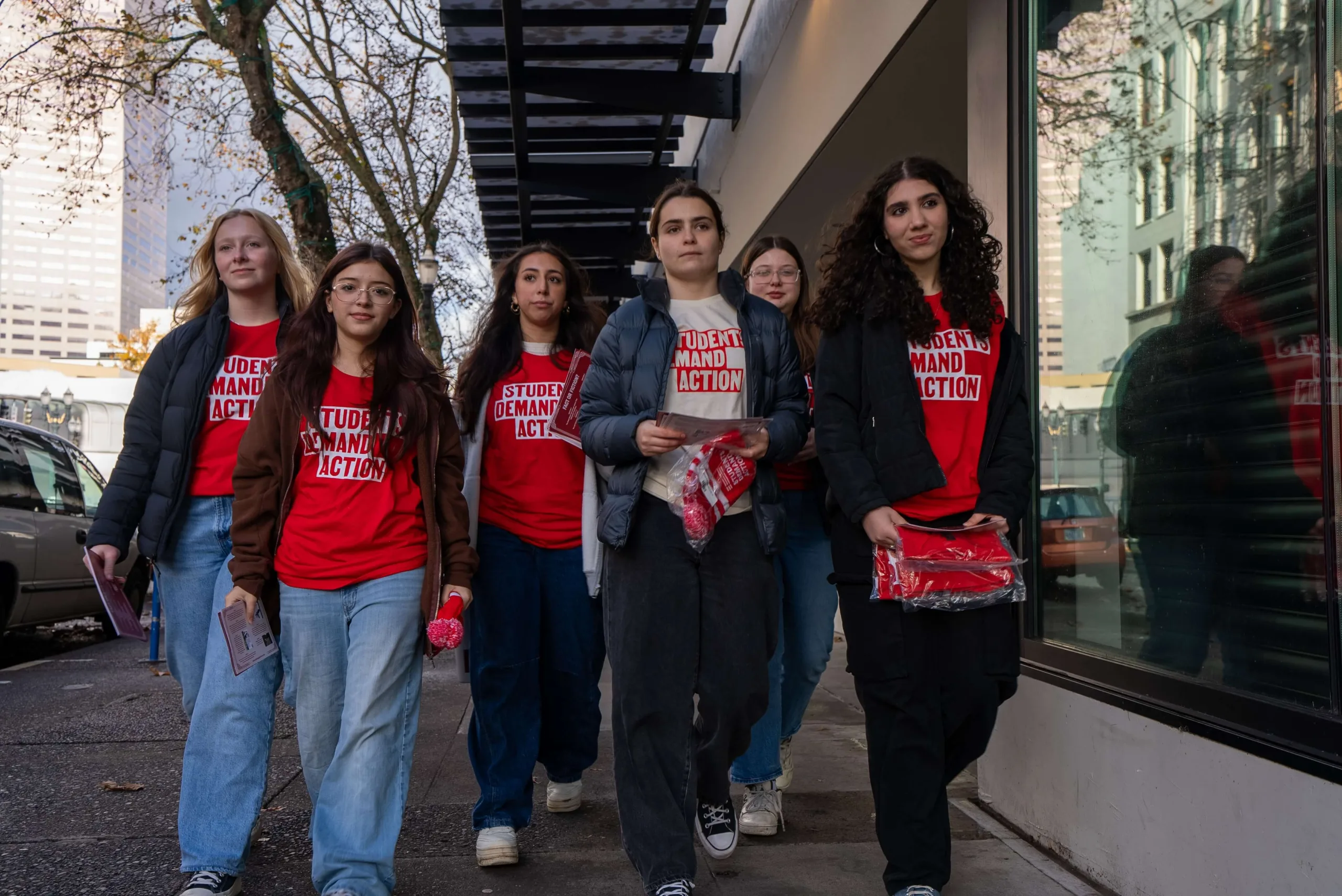 Six Students Demand Action volunteers walk down the street in Portland, Oregon, during an in-person activation for the Are You Good With That? campaign. They all are wearing red Students Demand Action t-shirts and are in-motion walking toward the camera.