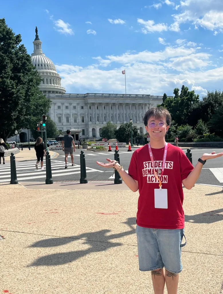 Bo, one of the Students Demand Action Creators, poses for a photo in front of the United States Capitol. Bo is wearing a red Students Demand Action t-shirt and denim shorts.