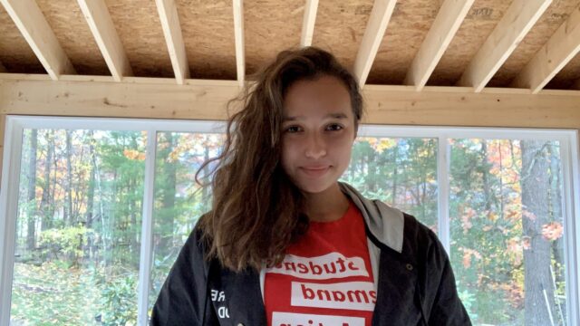 Students Demand Action volunteer Maddie Ahmadi poses wearing a red SDA t-shirt.
