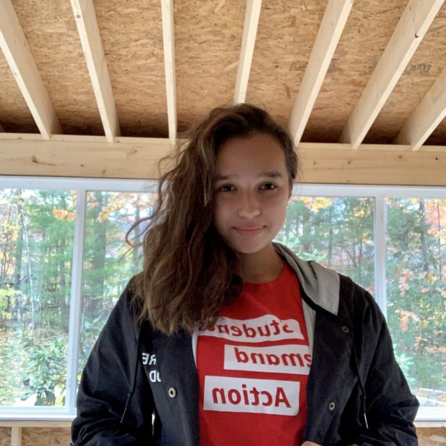 Students Demand Action volunteer Maddie Ahmadi poses wearing a red SDA t-shirt.