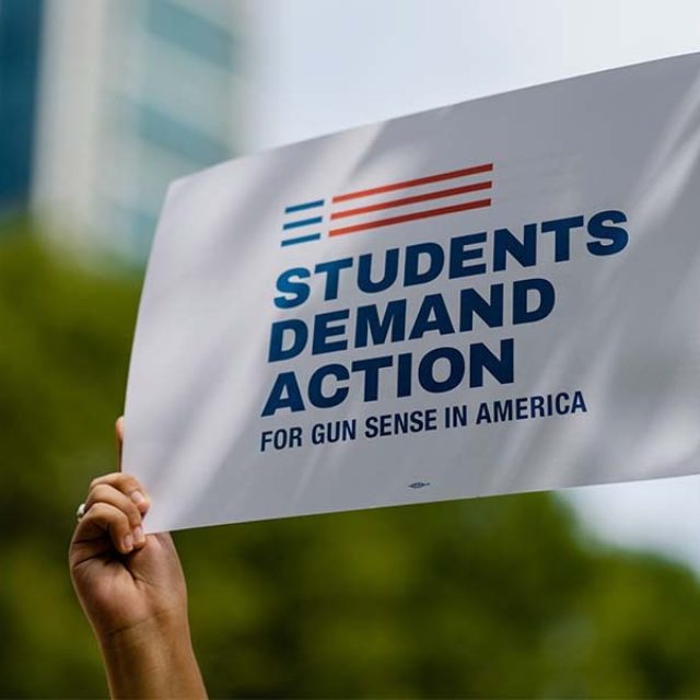 A person holds up a Students Demand Action sign in a crowd