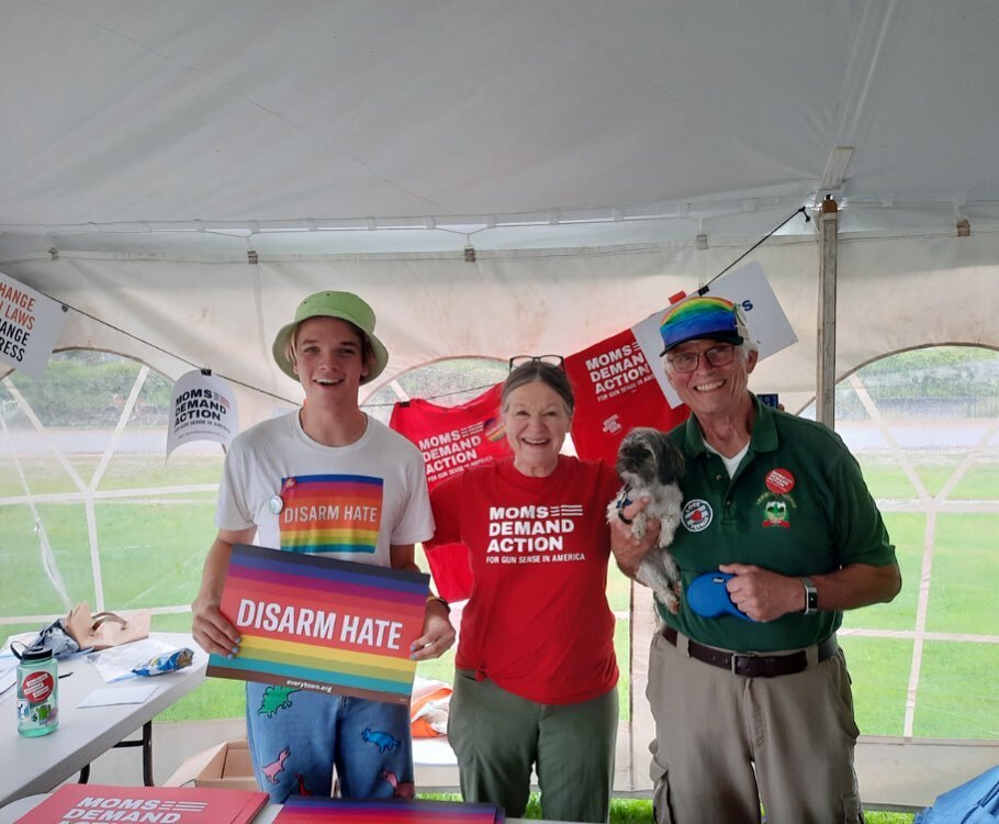 A Students Demand Action volunteer wearing a Disarm Hate t-shirt and holding a Disarm Hate rainbow sign, next to a Moms Demand Action volunteer