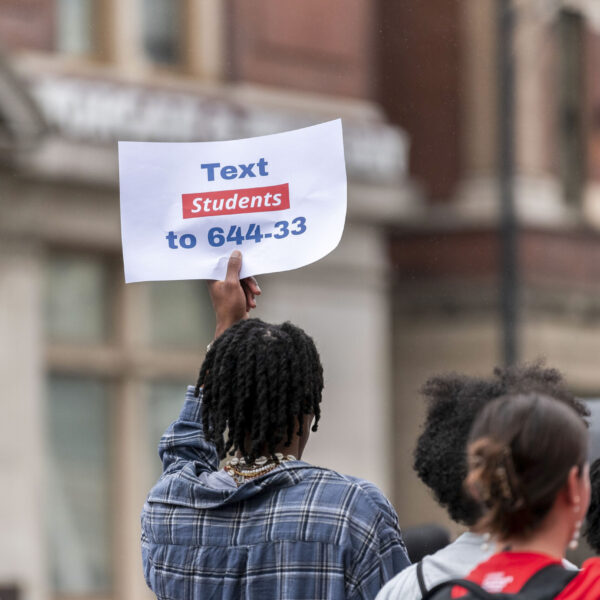 A student holds up a sign that says “Text Students to 644-33”