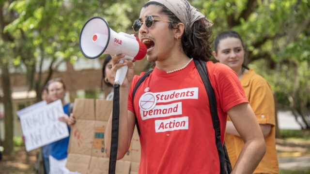 A Students Demand Action volunteer holds and speaks into a megaphone