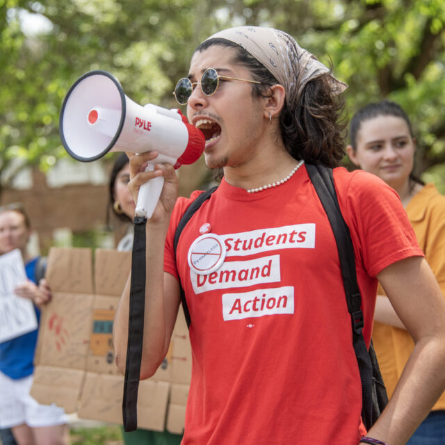A Students Demand Action volunteer holds and speaks into a megaphone