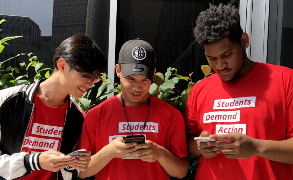 Three Students Demand Action volunteers texting on their phones