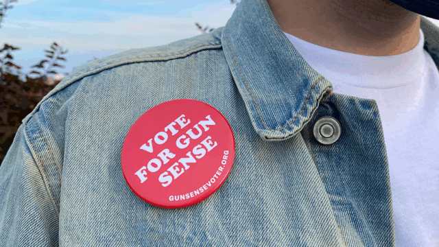 Featured image for the Gun Sense Voter Guide. A person wears a faded light-blue denim jacket and a white t-shirt. A red 