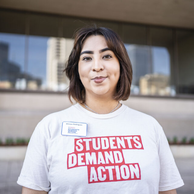A Students Demand Action volunteer wearing a white and red Students Demand Action shirt.