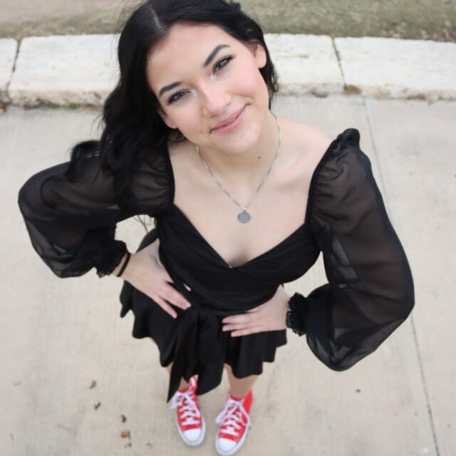 Hayden Presley, a Students Demand Action Text Team Captain, poses for a photo taken from a high angle. Hayden is wearing a black dress with bright red high-top sneakers.