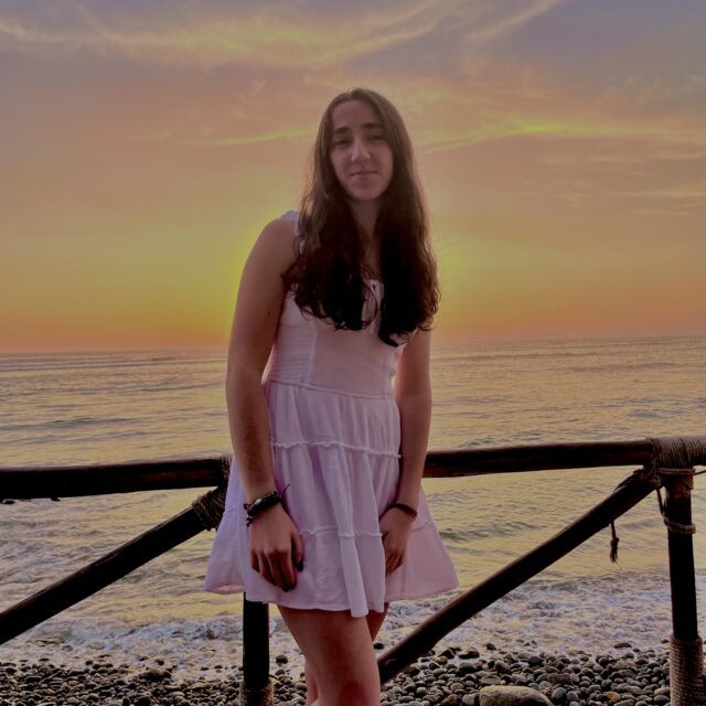 Gabi Iler, a Students Demand Action Text Team Captain, poses for a photo at sunset along a waterfront.