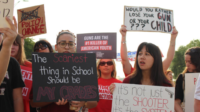 Students at a protest for gun safety hold signs that read