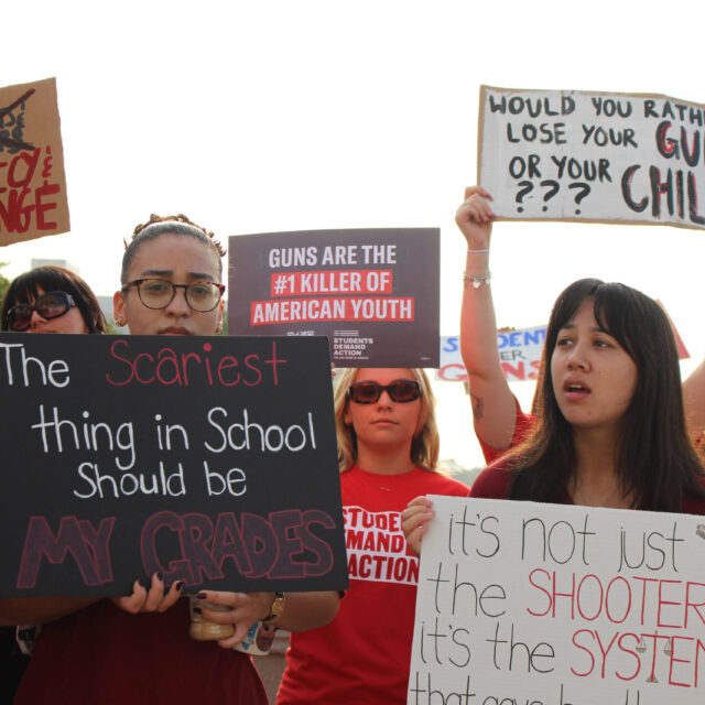 Students at a protest for gun safety hold signs that read 